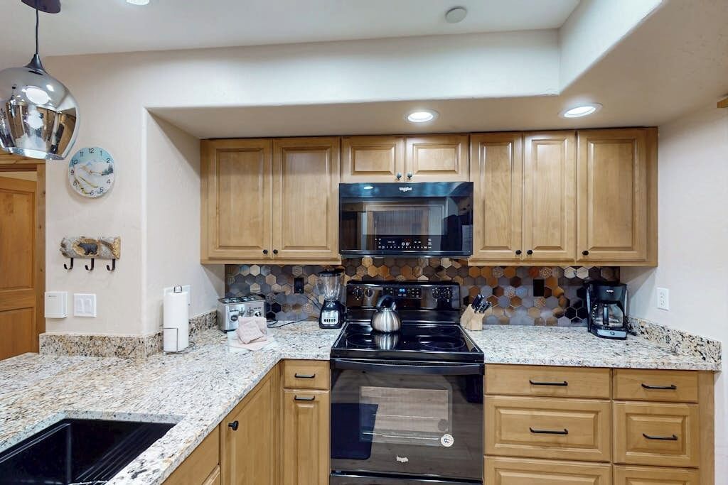 A kitchen with wooden cabinets, a black stove, and a microwave.