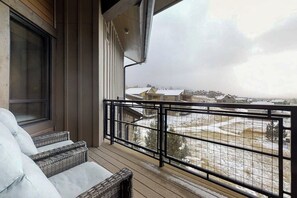 Ein Balkon mit Korbmöbeln und Blick auf eine verschneite Landschaft.