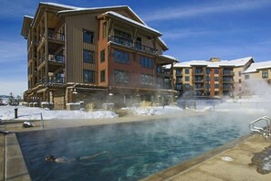 Ein Hotel mit Pool, Schnee auf dem Boden und blauem Himmel.