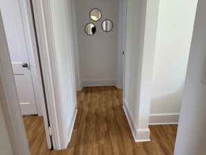 A hallway with wooden flooring, white walls, and three round mirrors on the wall. - Spacious 3BR Home • Near Caesars Virginia • Ideal for Families & Work Stays (Danville)