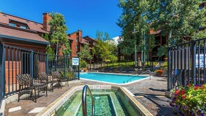A swimming pool with a 3 FT depth marker, surrounded by outdoor seating and a fenced area. - Deluxe condo with private patio, pool & hot tub (Steamboat Springs)