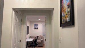 A hallway leading to a dining area with a table and chairs, a painting on the wall, and a door on the left. - Private Suite with Full Bath & Separate Entrance –  close to Tufts University (Winchester)