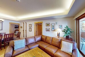Ein Wohnzimmer mit braunem Ledersofa, einem Holztisch und gerahmten Bildern an der Wand.