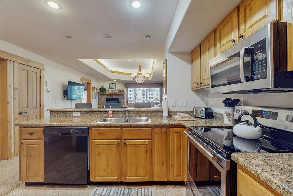 A modern kitchen with wooden cabinets, a dishwasher, a microwave, and a kettle.
