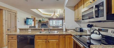 A modern kitchen with wooden cabinets, a dishwasher, a microwave, and a kettle.