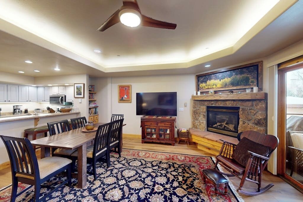 A spacious living room with a fireplace, a television, and a dining area with chairs and a table.