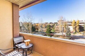 Ein Balkon mit Tisch und Stühlen, mit Blick auf ein Wohngebiet mit Bäumen und Gebäuden.