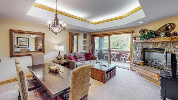 A spacious living area with a dining table, sofa, fireplace, and large windows. - Canyon Creek A304 - Top-floor mountain condo w/ a shared, heated pool, hot tub, & fitness room (Steamboat Springs)
