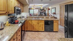 A kitchen with wooden cabinets, granite countertops, a built-in dishwasher, and a black refrigerator. - Canyon Creek A304 - Top-floor mountain condo w/ a shared, heated pool, hot tub, & fitness room (Steamboat Springs)