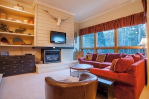 Ein Wohnzimmer mit Kamin, rotem Sofa und Fernseher.