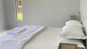 A bedroom with a bed, a window, and a door.