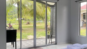 A bedroom with a bed, a sliding glass door to a patio, and a view of a garden.