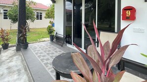 A covered outdoor area with a table and chairs, potted plants, and a red mailbox.