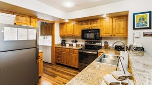 Una cocina moderna con armarios de madera, un refrigerador de acero inoxidable, un microondas y un horno.