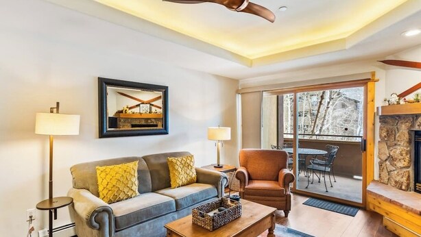 Una sala de estar con sofá, sillón, mesa de centro y chimenea.