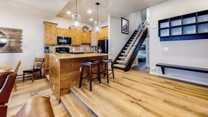 Una cucina moderna con mobili in legno, un'isola centrale con sgabelli, una scala e una panca integrata.