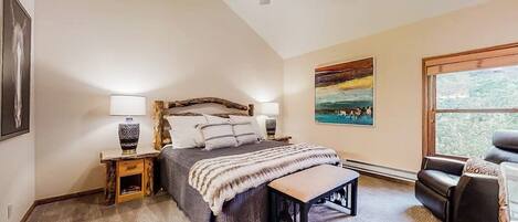 A bedroom with a bed, bedside tables, a bench, a ceiling fan, and a window.