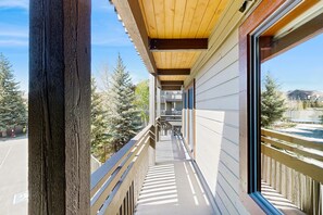 A covered outdoor corridor with wooden railings, a concrete floor, and a view of trees and buildings in the distance. - Clean Steamboat suite with washer/dryer, pool & hot tubs - near ski base (Steamboat Springs)