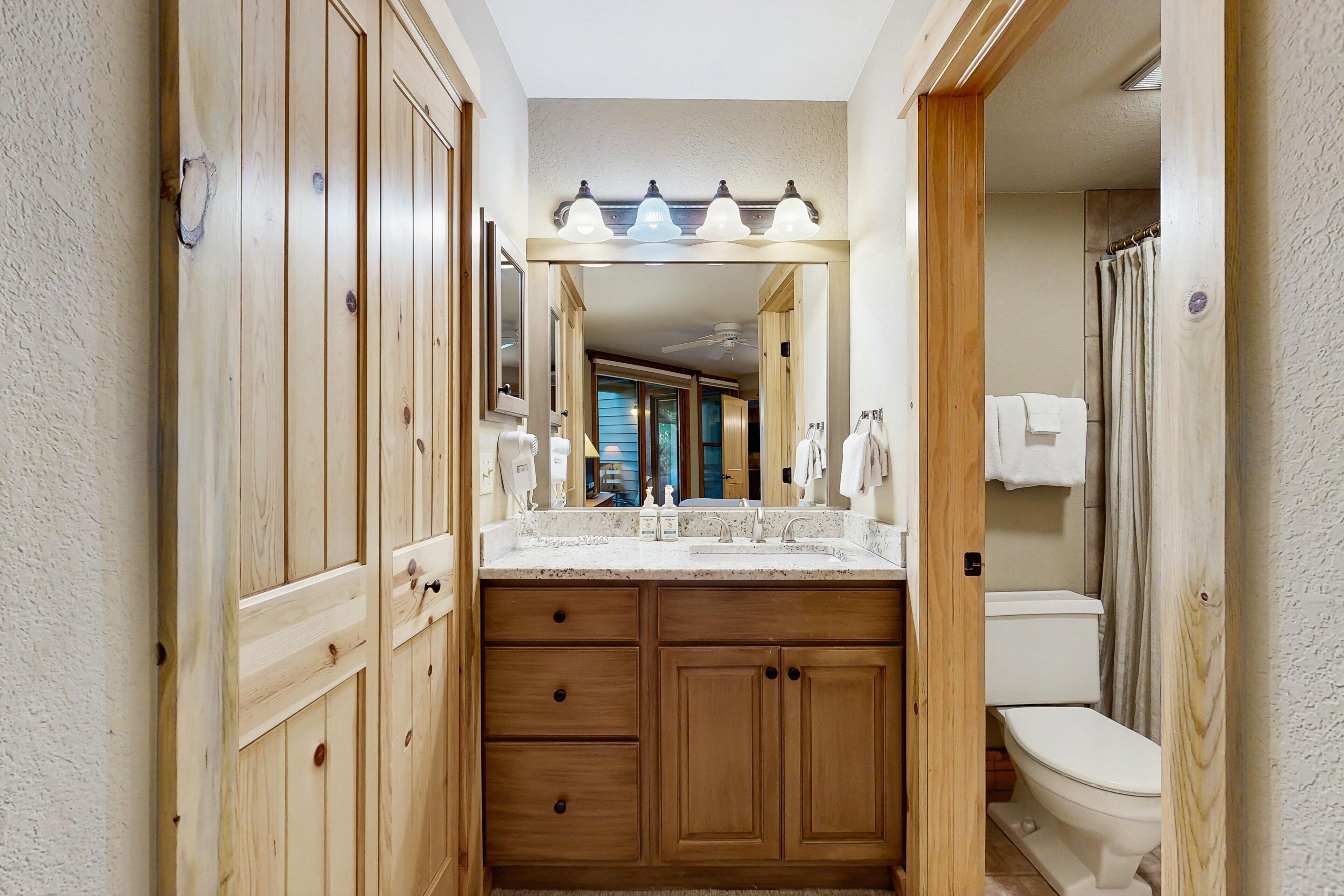 A wooden vanity with a sink, mirror, and overhead lighting.