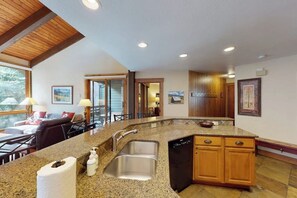 A kitchen with granite countertops, a stainless steel sink, wooden cabinets, and a built-in dishwasher. - Spacious Steamboat condo with pool, hot tubs, W/D - close to skiing & hiking (Steamboat Springs)