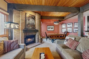 A cozy living room with a fireplace, a dining table, and a sofa. - Upgraded Steamboat condo with pool, hot tubs, & downtown shuttle service (Steamboat Springs)