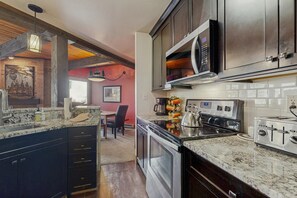 A kitchen with granite countertops, stainless steel appliances, and a dining area with a red wall and a painting. - Upgraded Steamboat condo with pool, hot tubs, & downtown shuttle service (Steamboat Springs)