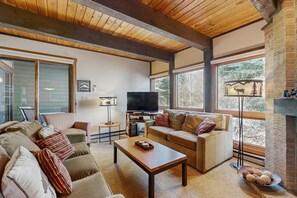 A living room with a wooden ceiling, a television, sofas, a coffee table, and a fireplace. - Upgraded Steamboat condo with pool, hot tubs, & downtown shuttle service (Steamboat Springs)