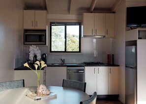 Een moderne keuken met een eethoek, met een magnetron, fornuis, spoelbak en kasten.