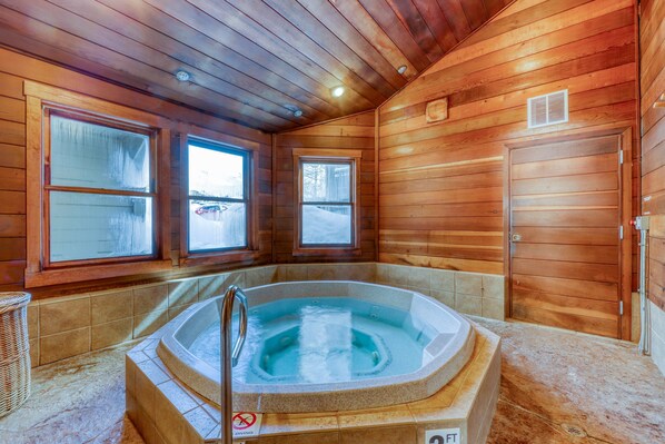 A wooden cabin with a hot tub, two windows, and a door.