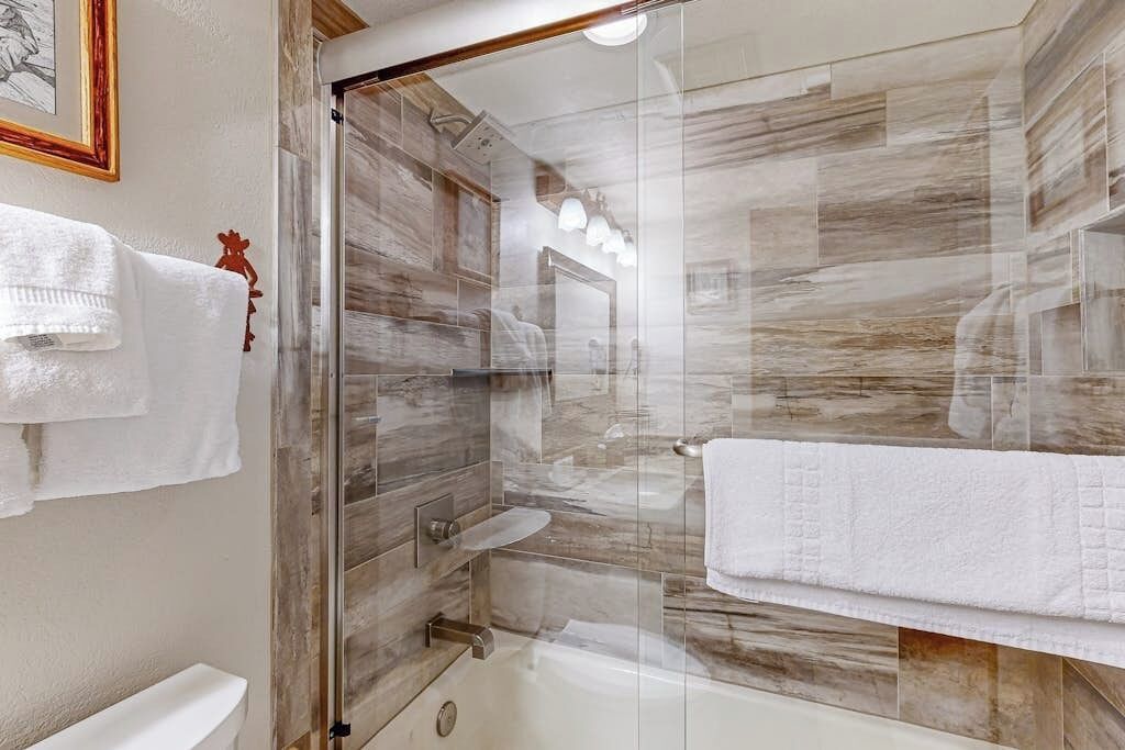 Un baño moderno con ducha envuelta en vidrio, inodoro blanco y bañera.