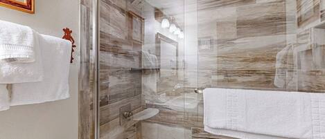 Un baño moderno con ducha envuelta en vidrio, inodoro blanco y bañera.