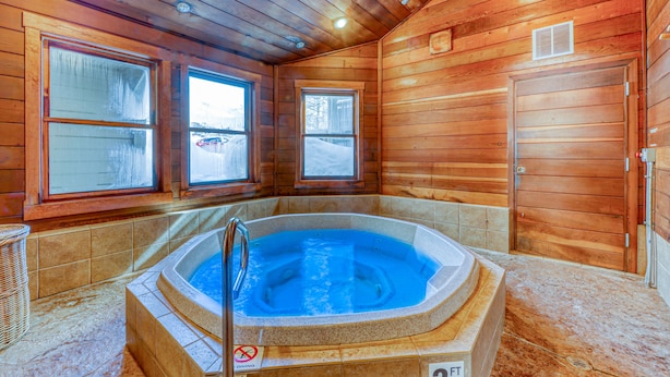 Eine Holzhütte mit Whirlpool, großen Fenstern und einer Tür.