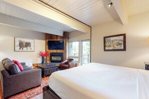 A hotel room with a large bed, a sofa, a fireplace, and artwork on the walls. - Remodeled, Ski-In/Ski-Out Studio w/ Fireplace & Shared Hot Tub - Near Hiking (Steamboat Springs)