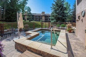 Ein Pool mit einer Steinterrasse, einer Liege und einer Pergola.