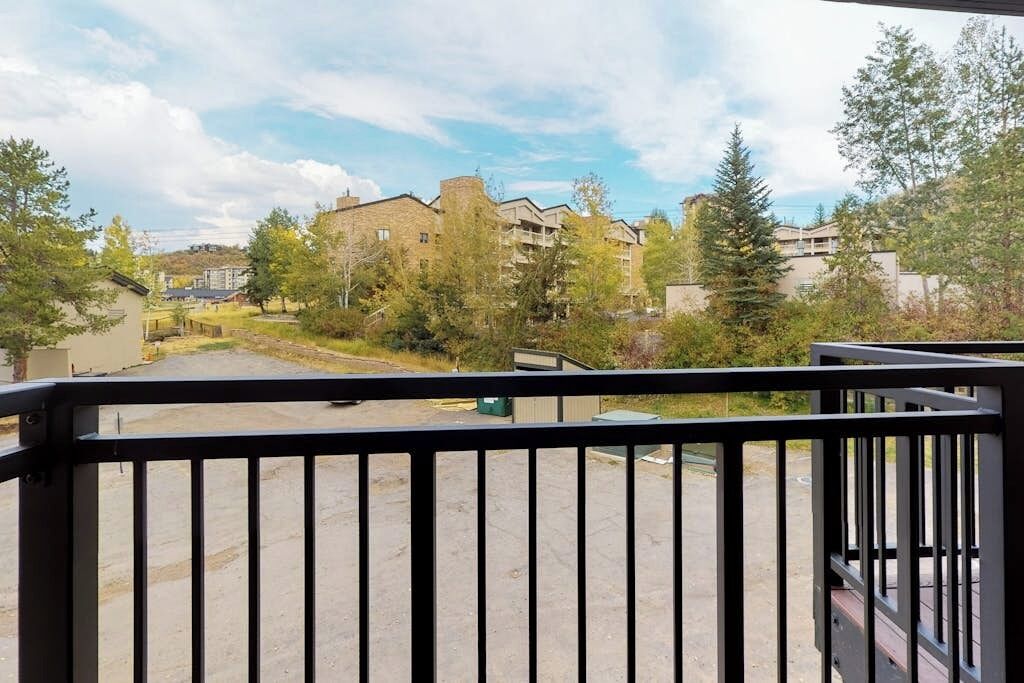 En balkong med utsikt över ett bostadsområde, inklusive byggnader och träd.