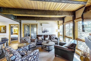 Ein geräumiges Wohnzimmer mit hoher Decke, großen Fenstern und einer Mischung aus modernen und traditionellen Möbeln.