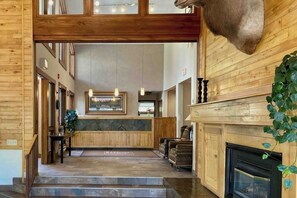 Ein Holzinnenraum mit Kamin, einer Bank und einer Treppe zu den oberen Stockwerken.