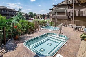 Ein Poolbereich auf dem Dach mit zwei Pools, umzäunt und an ein Gebäude mit Balkonen angrenzend.