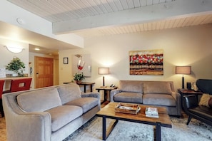 Ein Wohnzimmer mit zwei Sofas, einem Couchtisch und einem Gemälde an der Wand.