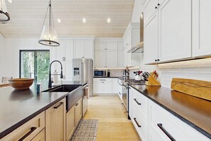 A modern kitchen with white cabinets, stainless steel appliances, and a wooden countertop.