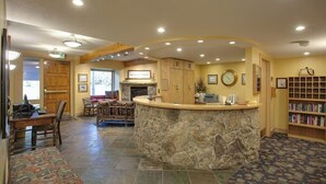 A reception area with a stone counter, wooden cabinets, a fireplace, and a bookshelf. - Top-Floor, Ski-In/Ski-Out Condo w/ Loft, Fireplace, Balcony & Shared Hot Tub (Steamboat Springs)