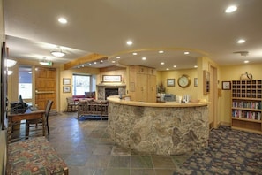 A reception area with a stone counter, wooden cabinets, a fireplace, and a bookshelf. - Top-Floor, Ski-In/Ski-Out Condo w/ Loft, Fireplace, Balcony & Shared Hot Tub (Steamboat Springs)