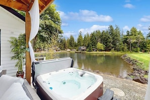 A hot tub outside a building with a view of a lake and trees.