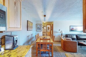 A compact living space with a dining area, a coffee machine, a sofa, and a lamp.