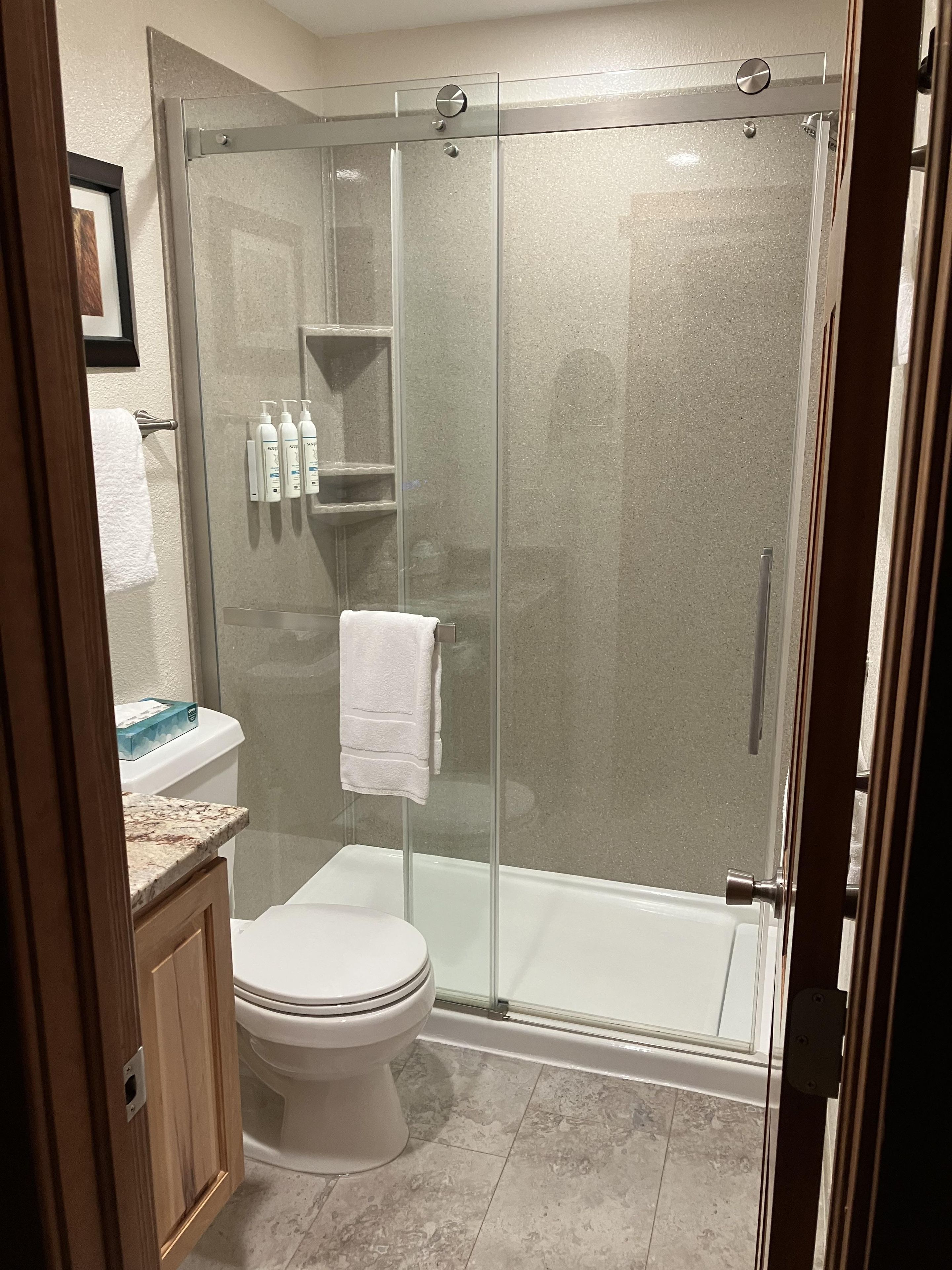 Ein modernes Badezimmer mit einer gläsernen Dusche, einer Toilette und einem Waschtisch mit Marmorplatte.