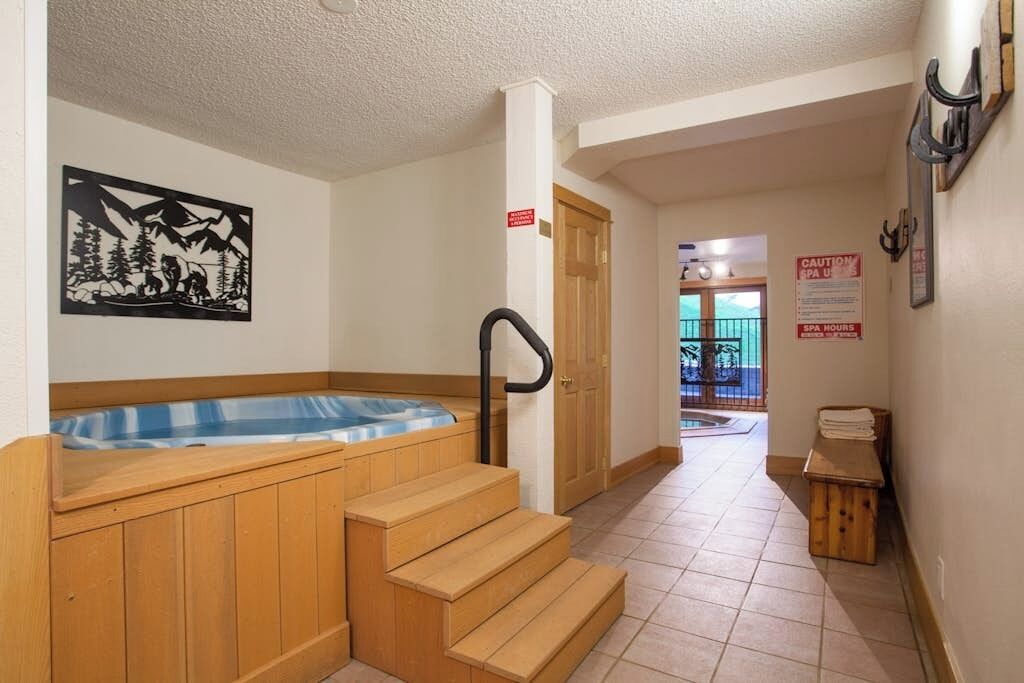 Un espace détente avec un jacuzzi, des marches en bois, une porte et une vue sur l’extérieur.