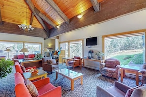 A spacious living area with a high ceiling, large windows, and a view of a golf course. - Quaint, ski-in/ski-out retreat w/ shared hot tub, sauna, and fenced-in backyard (Steamboat Springs)