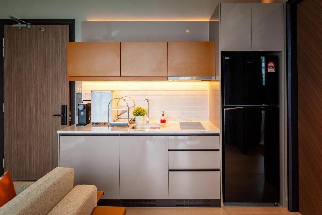 A compact kitchen with a built-in refrigerator, a coffee maker, and a sink.