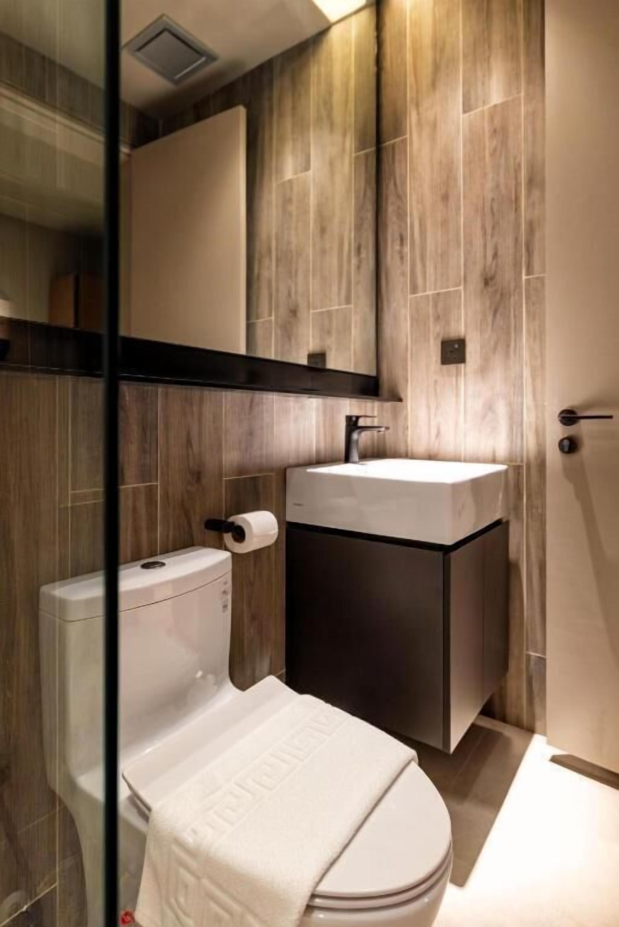 A modern bathroom with a toilet, sink, and mirror.