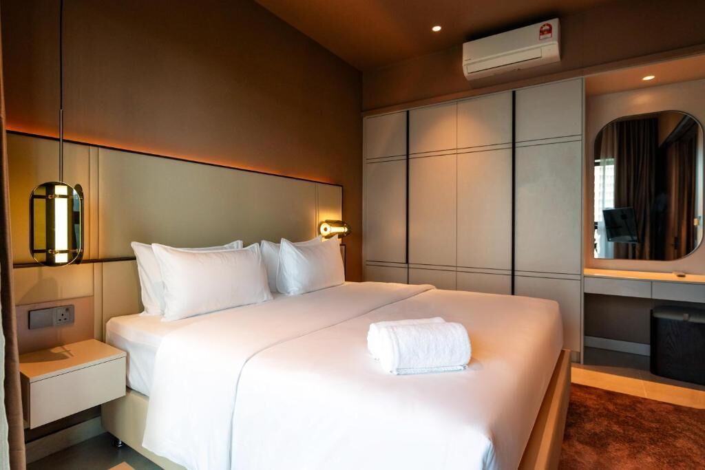 Una habitación de hotel con cama, mesitas de noche, un espejo y un armario.